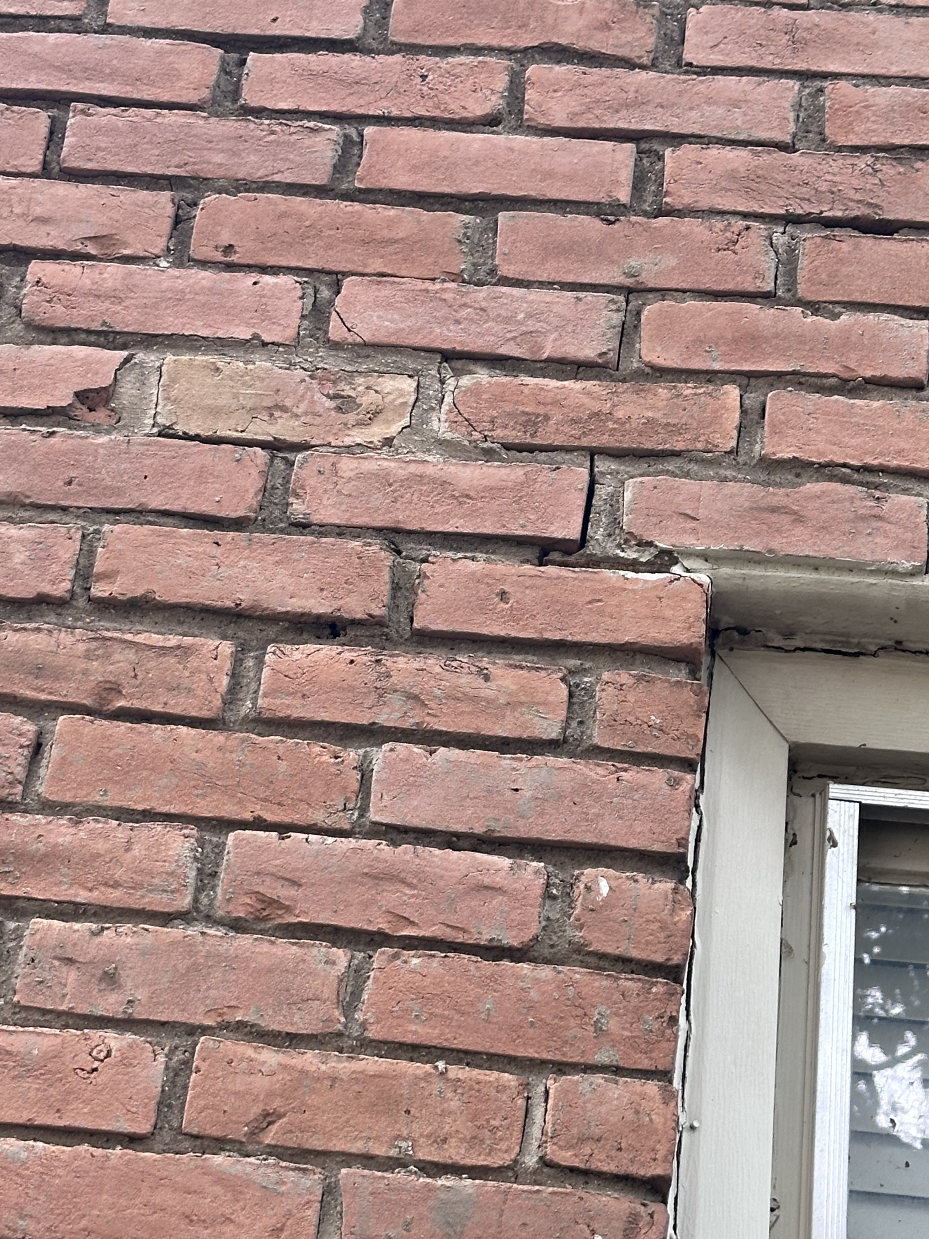 Close-up of spalling brick damage on a Fort Worth home showing flaked faces and exposed brick core